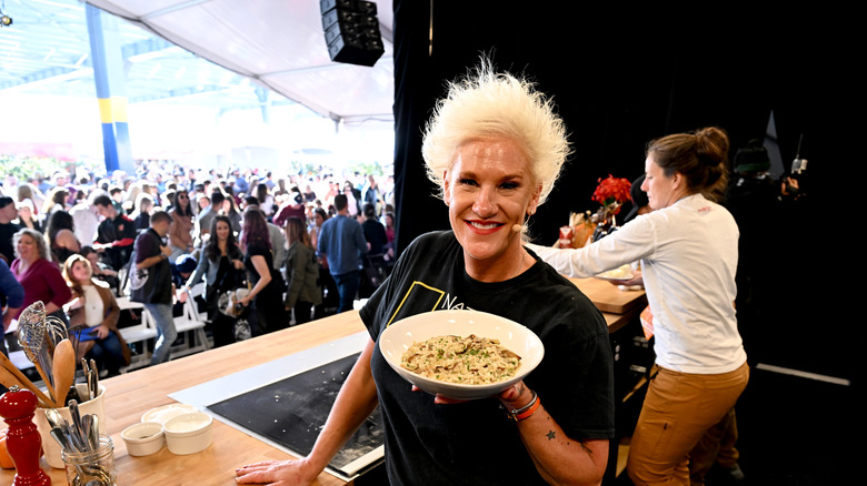 Anne Burrell holding a bowl of pasta on stage