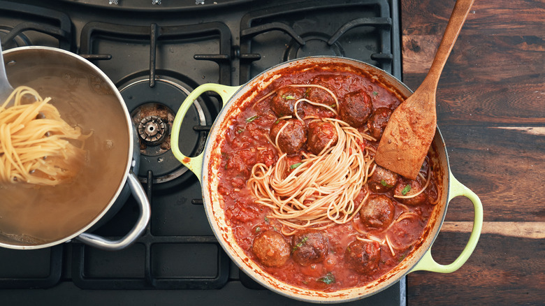 Boiled spaghetti and pot of meatballs with sauce