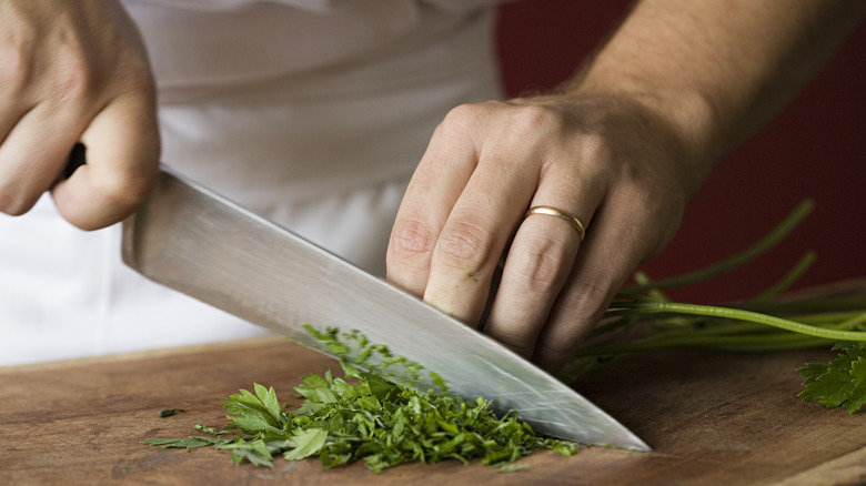 person chopping herbs with knife