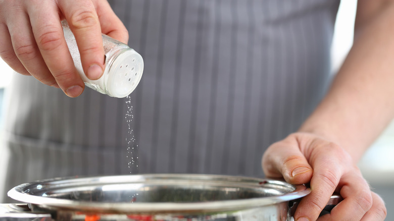 man adding salt to pot