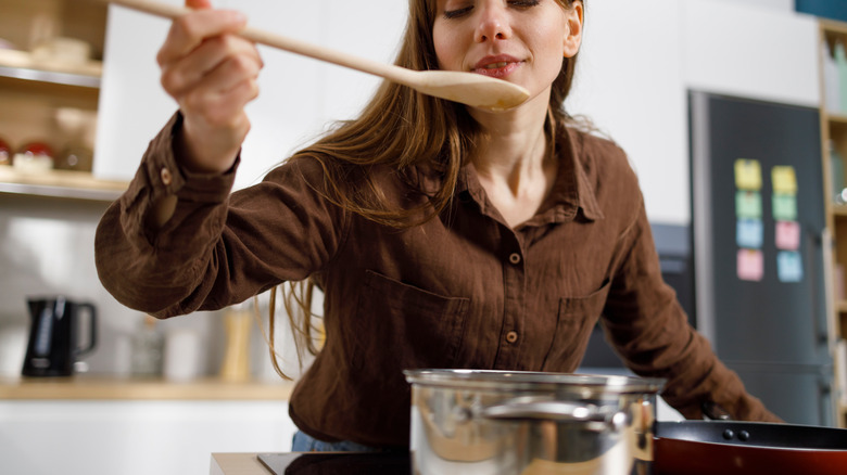 women tasting food in kitchen