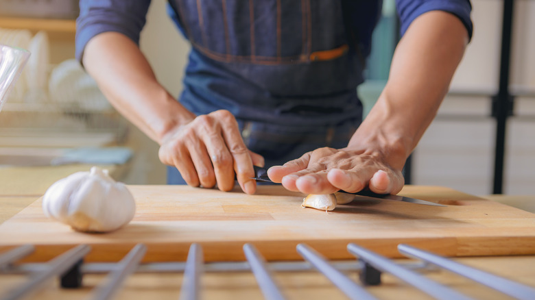 person smashing garlic on cutting board