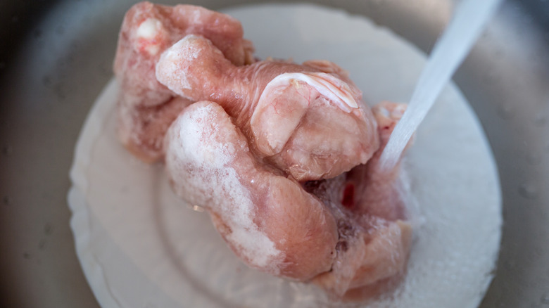 Frozen chicken under running water