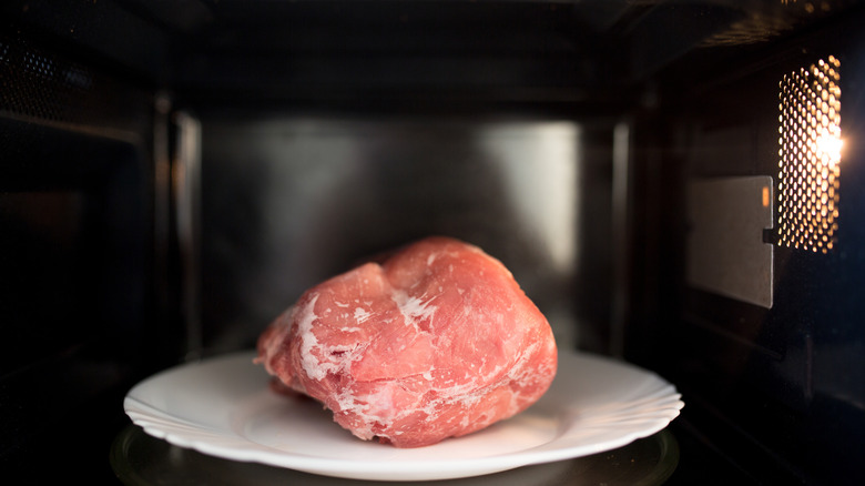 Pork defrosting inside a microwave