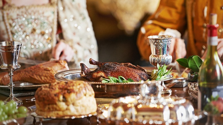 Close-up of two people at royal banquet, showing food