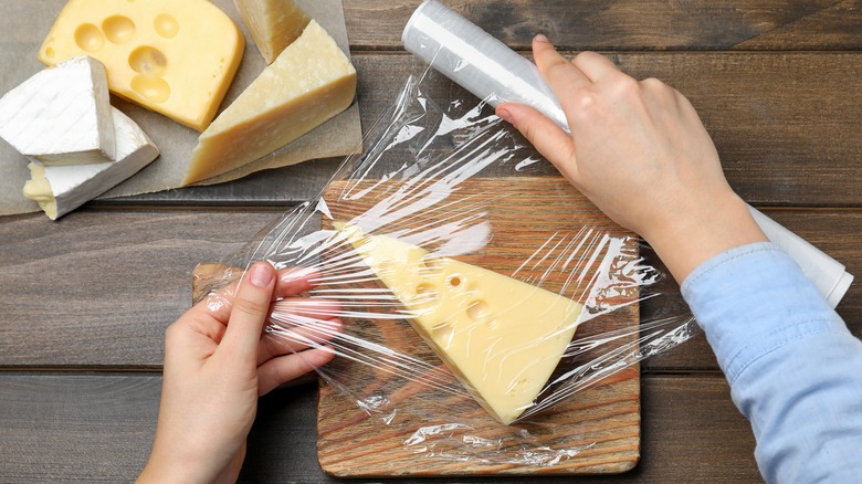 Person covering cheese in wrap