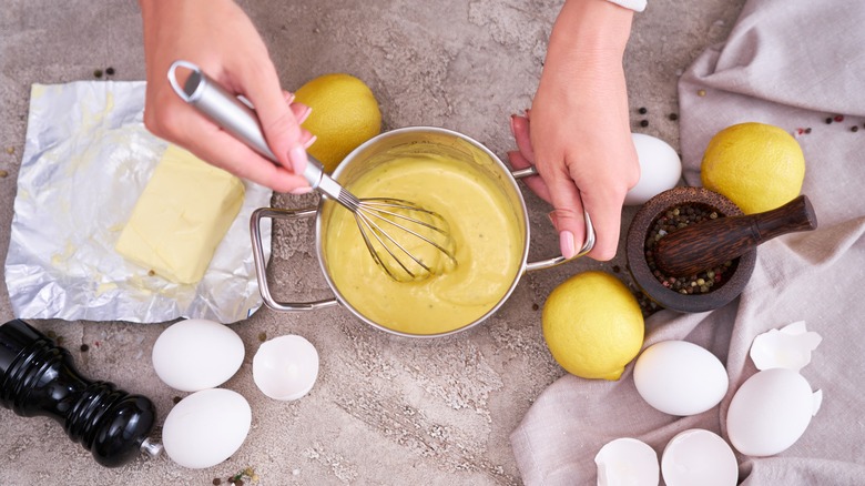 Woman making hollandaise sauce in pan with whisk