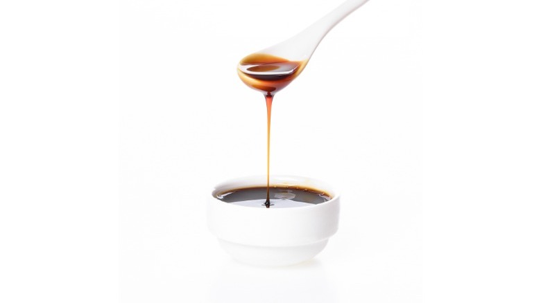 spoon and white bowl of brown molasses