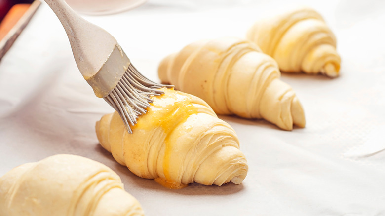 Brushing egg onto croissants with a silicone brush