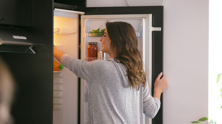 woman reaching into refrigerator