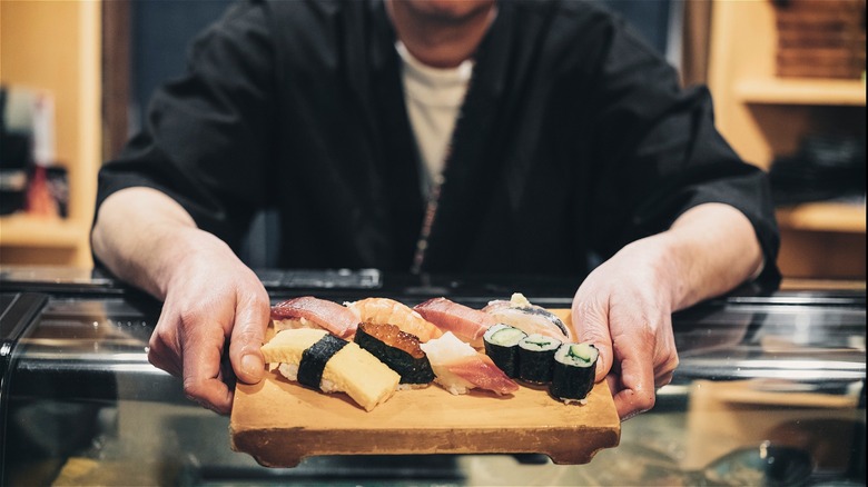 sushi chef offering a plate