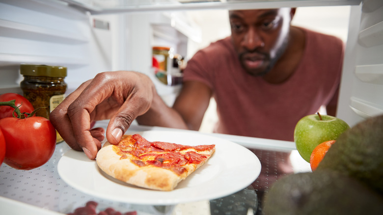 Man taking pizza from fridge