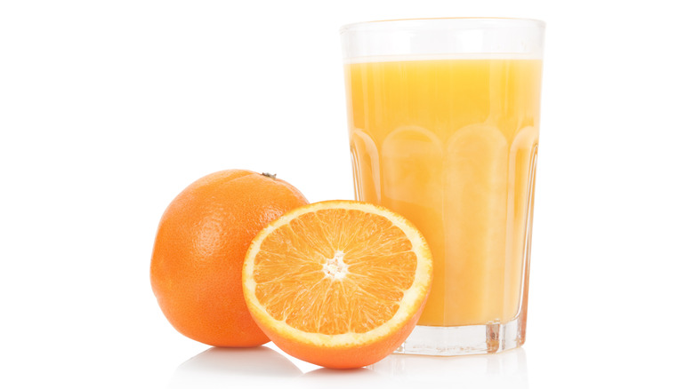 Glass of orange juice and fresh oranges