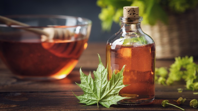 Glass bottle and bowl of maple syrup