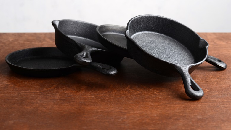 pile of cast iron skillets on wood table