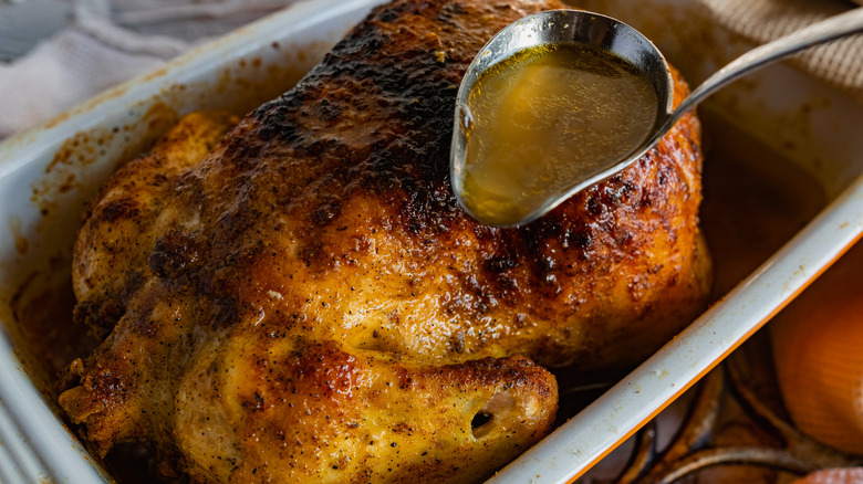 pouring chicken water over browned rotisserie