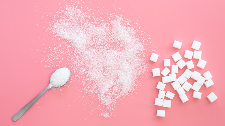 Sugar and sugar cubes on pink background