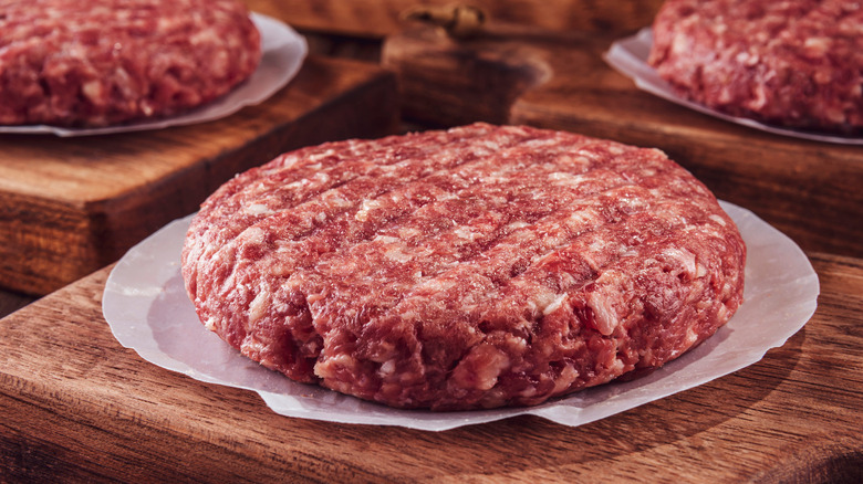 raw ground beef patties on boards