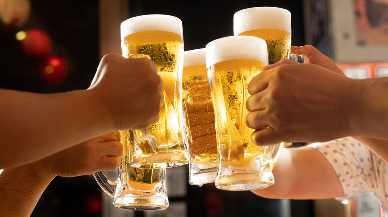 four people toasting with beers