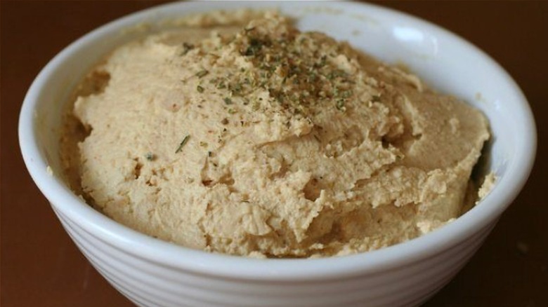 Bowl of smooth hummus with a sprinkle of herbs