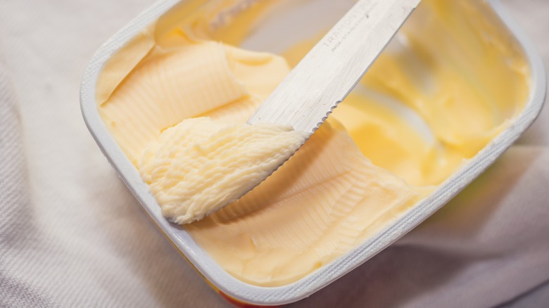 Knife scooping margarine from container