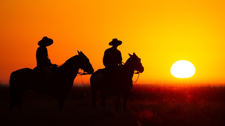 Cowboys riding at sunset