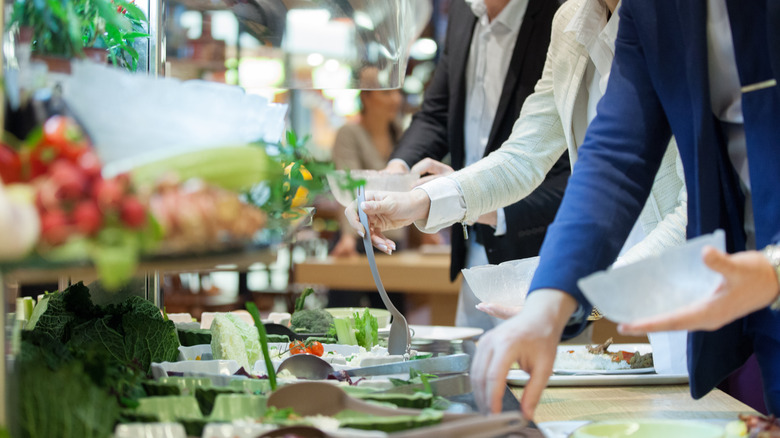 People serving at a salad bar