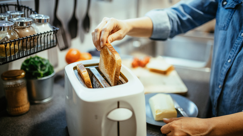 Man taking slices of toasted bread out of a toaster