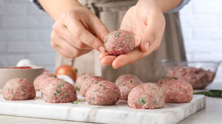 Hands forming meatballs on marble