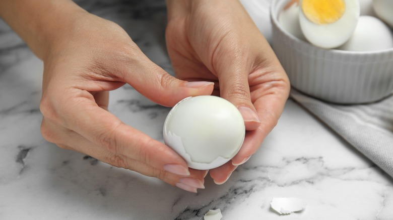 woman peeling hard-boiled egg