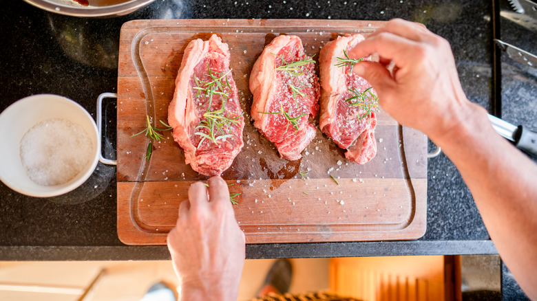 person seasoning meat with salt