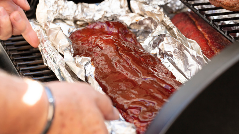 hands wrapping meat in foil