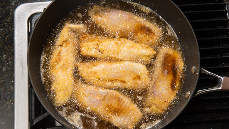 Close up of fish frying in pan