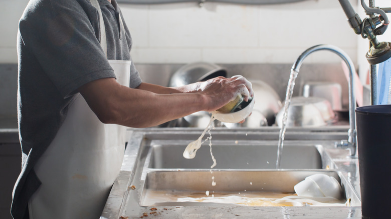 Person washing dishes in apron 