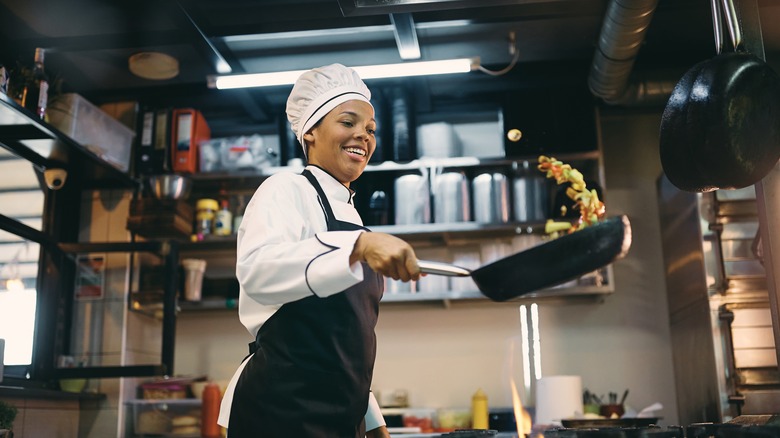 Female chef tossing food