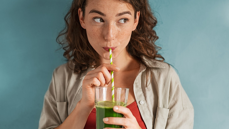 woman drinking a green smoothie