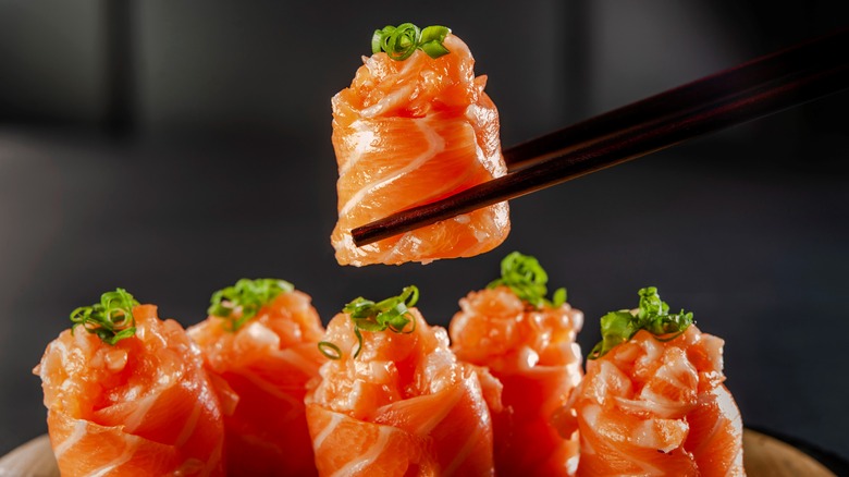 Salmon roll held by chopsticks