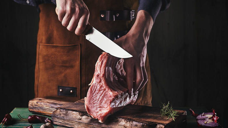 Man in apron cutting meat