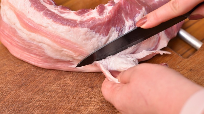Hand trimming fat from pork