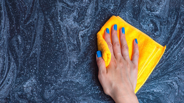 Hand wiping black marble countertop