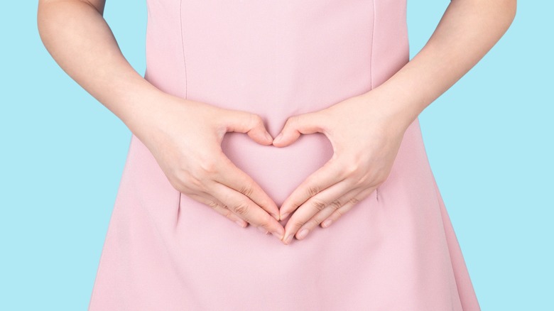 Woman hands in heart over tummy