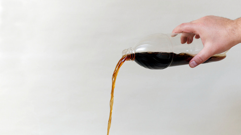 person pouring coke from bottle