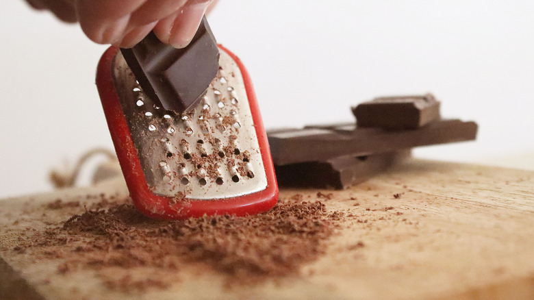 Person grating chocolate on wooden board