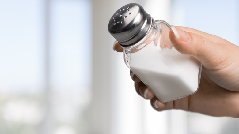 Person holding salt shaker