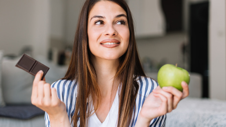 Woman holding apple and chocolate