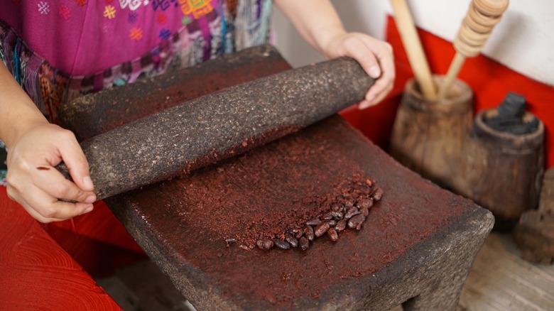 mayan woman grinding cacao beans