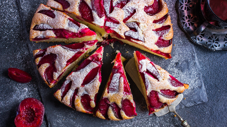 rustic plum cake on dark background , top view