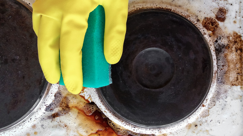 gloved hand cleaning dirty stove