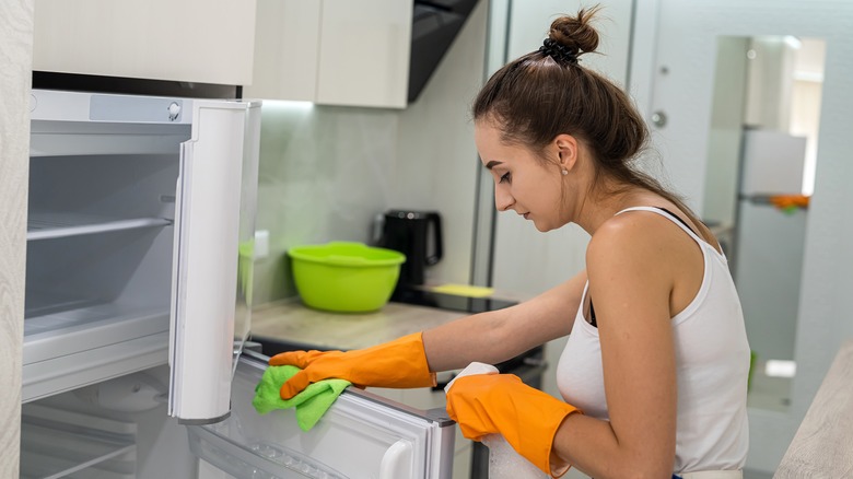 woman wiping down fridge