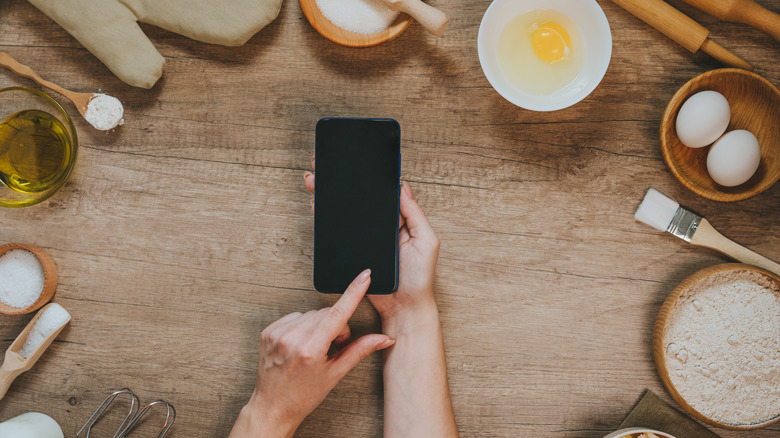 hands touching phone near eggs